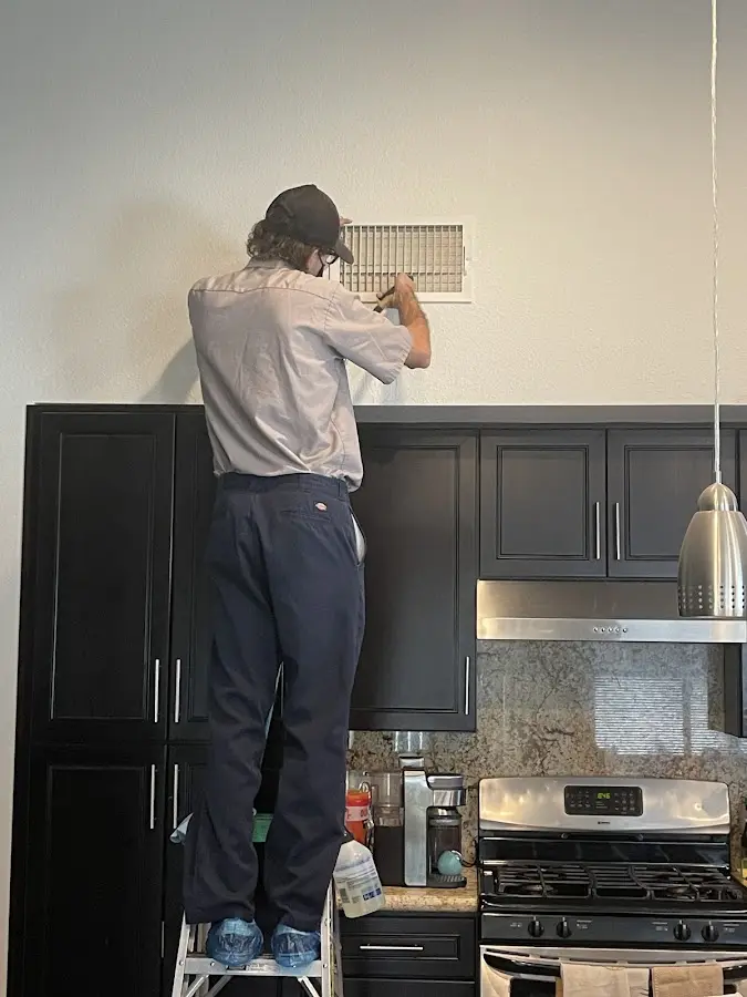 Technician inspecting an air vent during HVAC service in North Las Vegas